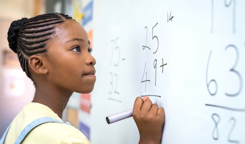 Girl writing maths equations on a whiteboard